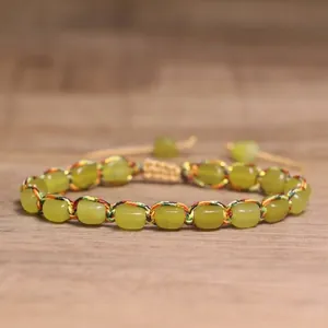 Close-up of the intricate colorful woven thread and smooth green stone beads