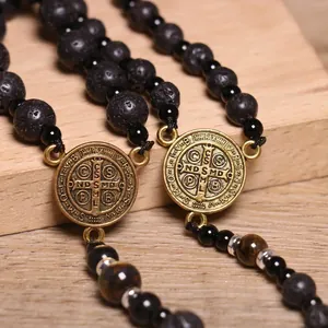 Detalle de la medalla de San Benito con piedra de lava negra y cuentas de ojo de tigre.