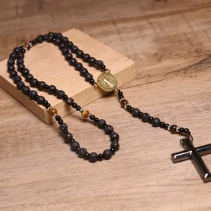 Vista detallada de collar religioso tipo rosario con cuentas de lava y cruz de hematita negra