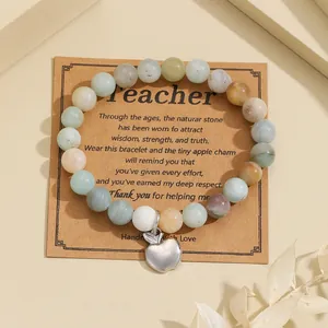 Detailed view of natural stone beads and silver apple charm on a kraft gift card