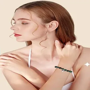 Detail of a green natural stone beaded bracelet with heart charm on a female wrist