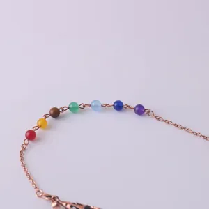 Primo piano di sette perle di cristallo chakra su una catena in oro rosa con chiusura a moschettone