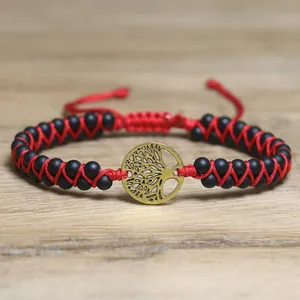Close-up of the Tree of Life charm on a red and black woven adjustable stone bracelet