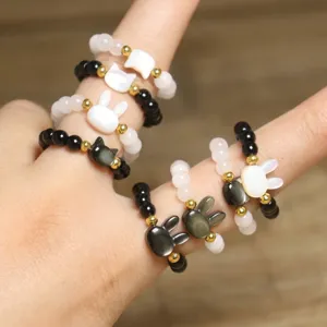 Close-up of handmade beaded rings with cute shell animal charms on elastic bands.