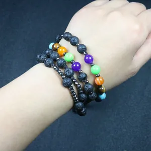 Detailweergave van handgemaakte chakra lavasteen en hematiet kralenarmbanden om een pols