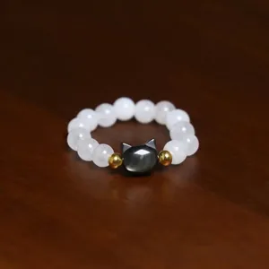 Detail shot of a handmade elastic ring featuring white shell pearls and a cat bead