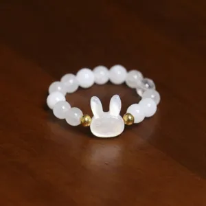 Macro detail view of white shell rabbit charm and natural stone beaded elastic ring