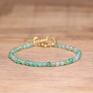 Close-up of a handmade green faceted natural stone bead bracelet with gold hardware