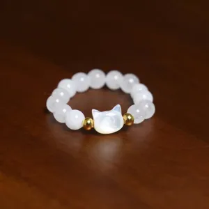 Detailed macro view of a beaded ring with white shell pearls and a cat head charm