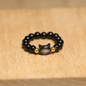 Close-up detail of a handmade elastic ring featuring a cute cat shaped shell bead