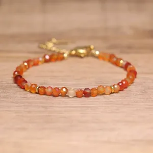 Close-up of faceted natural orange stone beads on an adjustable gold bracelet