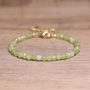 Macro view of faceted green natural stone beads on a bohemian style adjustable bracelet.