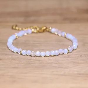 Close-up view of faceted opal-like beaded bracelet with adjustable gold chain on wood.