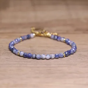 Macro detail of faceted blue natural stone beads and gold spacers on a delicate bracelet