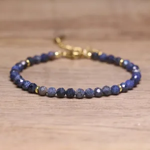 Detail view of a handmade blue faceted natural stone beaded bracelet with gold spacers.