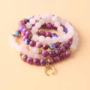 Primer plano de cuentas mala de cuarzo rosa y jaspe imperial morado con dije de luna dorada