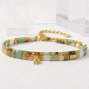 Close-up detail of Tila bead bracelet featuring natural stone and a gold sun charm pendant