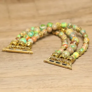 Detailweergave van getextureerde stenen kralen en gouden connectoren op Apple Watch bandje
