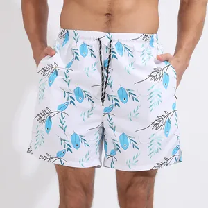 Détail d'un short de plage pour homme avec des imprimés de feuilles turquoise et motifs.