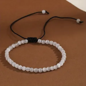 Detailed view of 4mm natural white stone beads on an adjustable black woven bracelet.