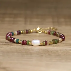 Handmade tourmaline beaded bracelet with a baroque pearl on a wood surface