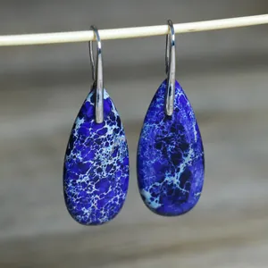 Macrodetail van elegante blauw gemarmerde keizersteen druppelvormige oorbellen
