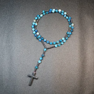 Detail of handmade rosary necklace with blue striped agate beads and hematite cross.