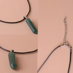 Macro detail view of a green hexagonal quartz crystal pillar pendant on a black cord necklace