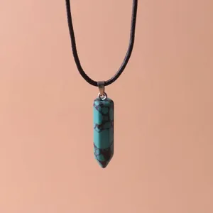 Close-up of a hexagonal turquoise stone pillar pendant on a black cord necklace