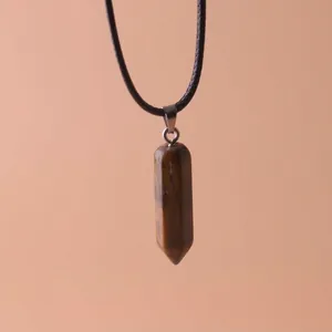 Macro view of natural tiger eye hexagonal column pendant on minimalist black cord