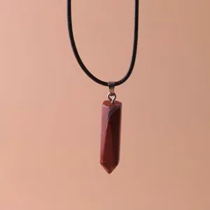 Close-up detail of a hexagonal red jasper stone pillar pendant on a black cord necklace
