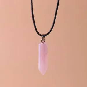 Macro detail of the hexagonal rose quartz crystal pendant hanging on a black cord