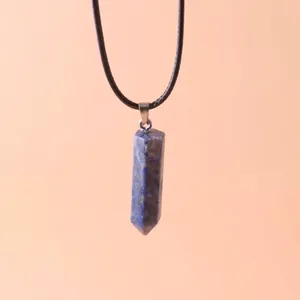 Close-up of a hexagonal blue lapis lazuli crystal pendant on a black cord necklace.