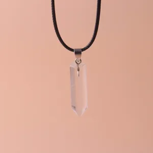 Macro detail showing a clear hexagonal quartz crystal point pendant on a black cord