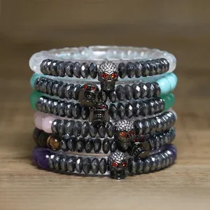 Close-up of gothic faceted hematite bracelets with red-eyed skull charms on wood