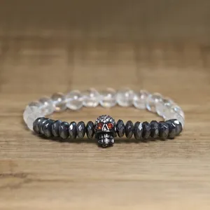 Detailed view of a gothic skull charm bracelet featuring hematite beads on wood
