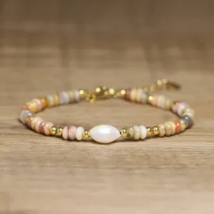 Macro detail of handmade natural stone beaded bracelet featuring a central baroque pearl