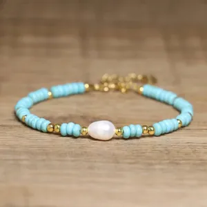 Detailed view of baroque pearl and turquoise beaded bracelet on a wood surface.
