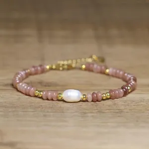 Detail view of a handmade bracelet with a baroque pearl and pink natural stone beads