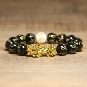 Vue détaillée d'un charme Pixiu doré sur un bracelet de richesse en perles noires.