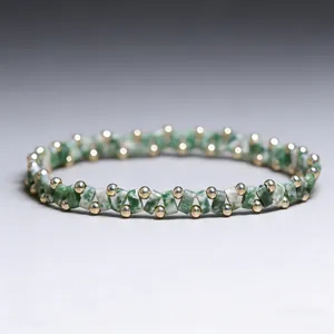 Macro view of green stone beads and small gold round beads on handmade elastic bracelet