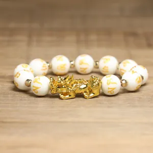 Vue détaillée d'un charm Pixiu doré et de perles gravées de mantras sur ce bracelet de richesse