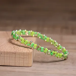 Detailed view of a green stone beaded bracelet with metal spacers on a wooden block