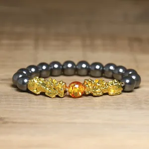 Vue détaillée du bracelet Pixiu avec perles métalliques et pierre centrale orange.