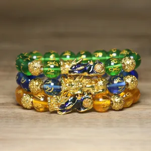 Détail de trois bracelets en perles Pi Yao avec les caractères dorés du mantra sacré