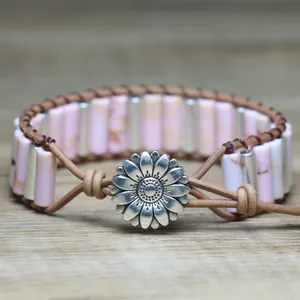 Close-up macro view of pink stone tube bracelet featuring a metal daisy flower clasp