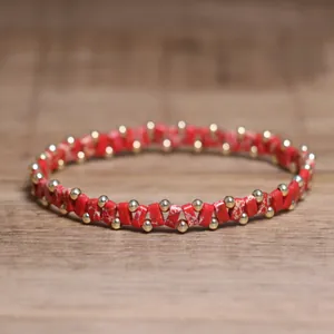 Close-up of a handcrafted red marble stone bead bracelet with gold accents.