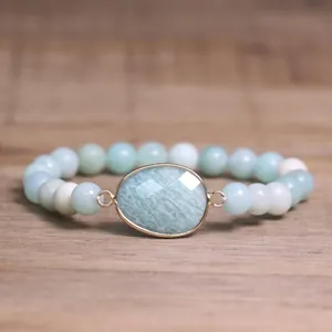 Vue détaillée d'une pierre naturelle vert clair facettée sertie d'or sur un bracelet perlé