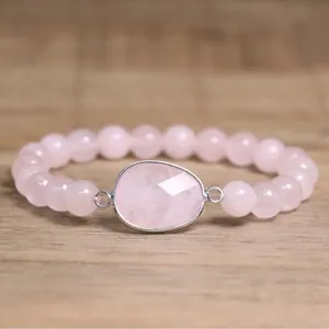 Gros plan d'un bracelet en quartz rose naturel avec un grand pendentif en pierre facettée.