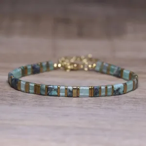 Detailed macro view of geometric turquoise natural stone and gold Tila bead bracelet